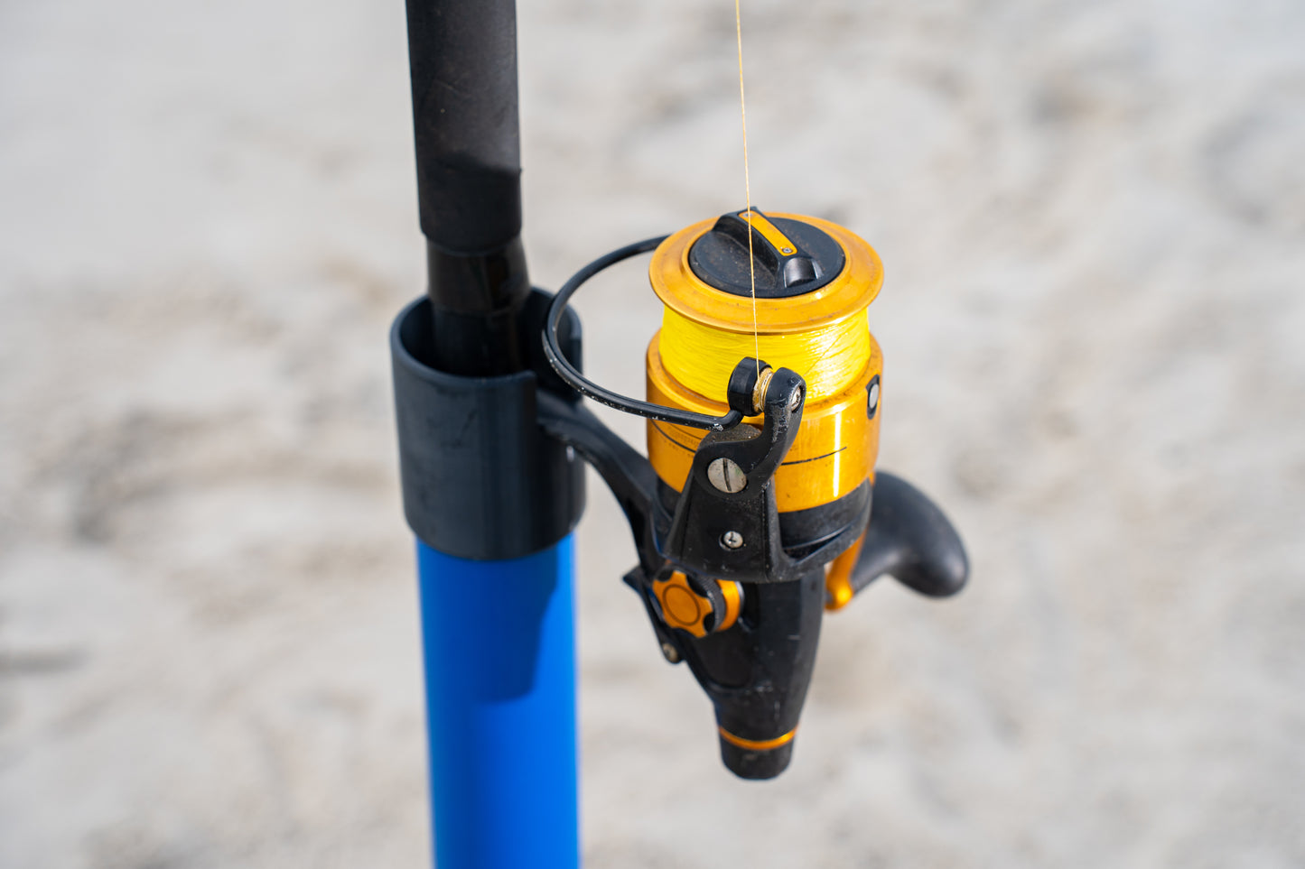 Custom blue aluminum surf fishing rod holder beach spike cap close up holding fishing rod