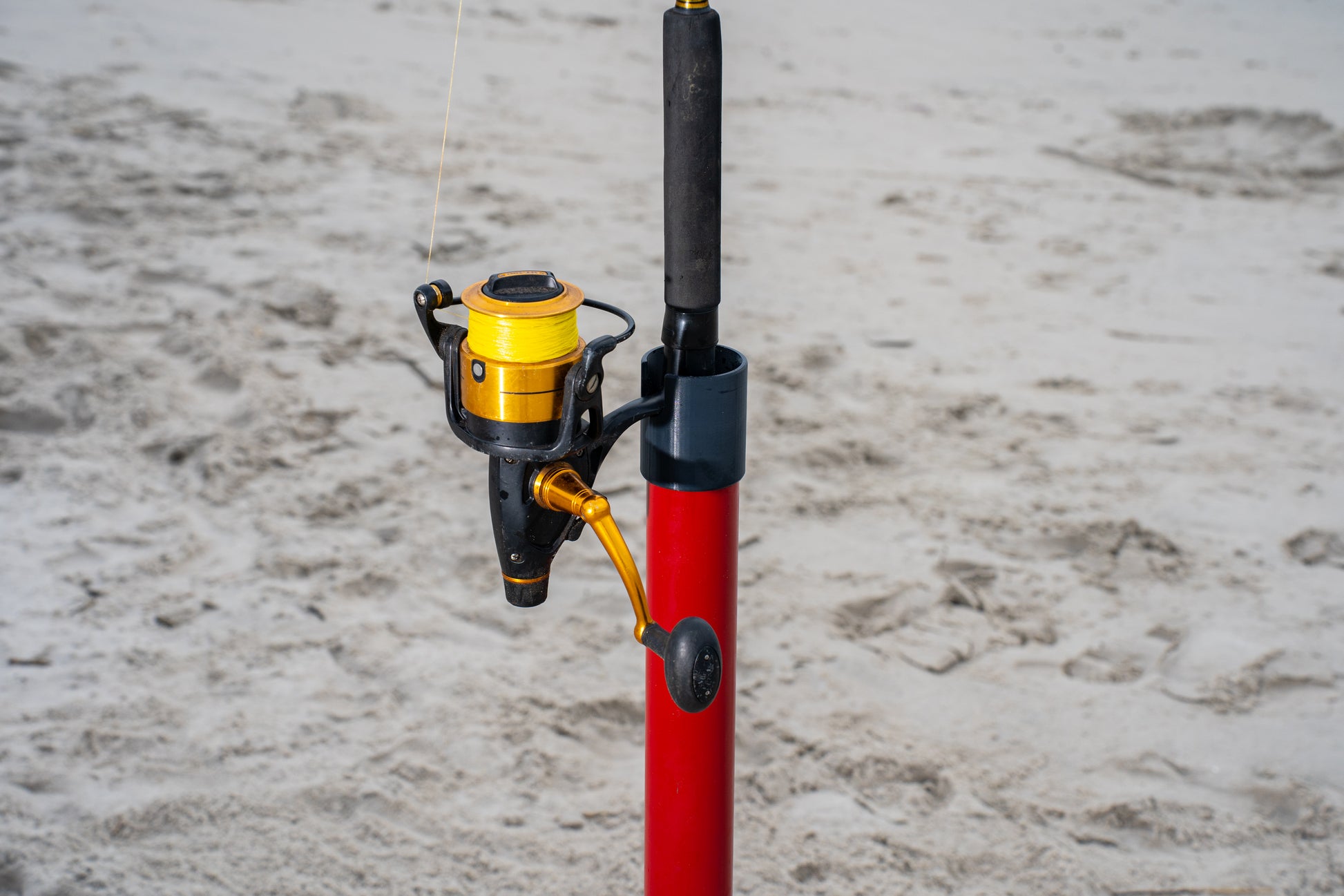 Custom red aluminum surf fishing rod holder beach spike close up