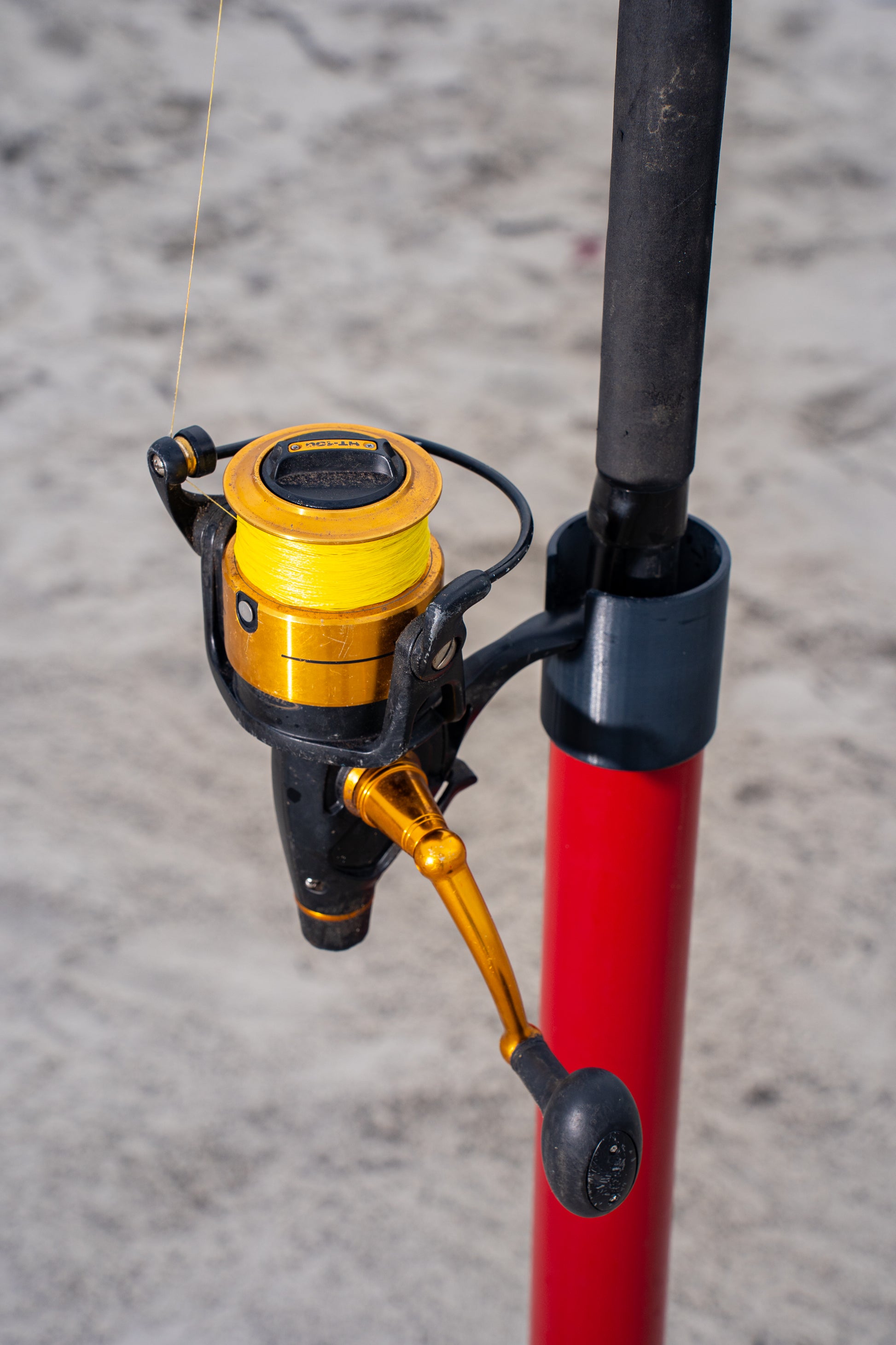 Custom red aluminum surf fishing rod holder beach spike close up holding rod