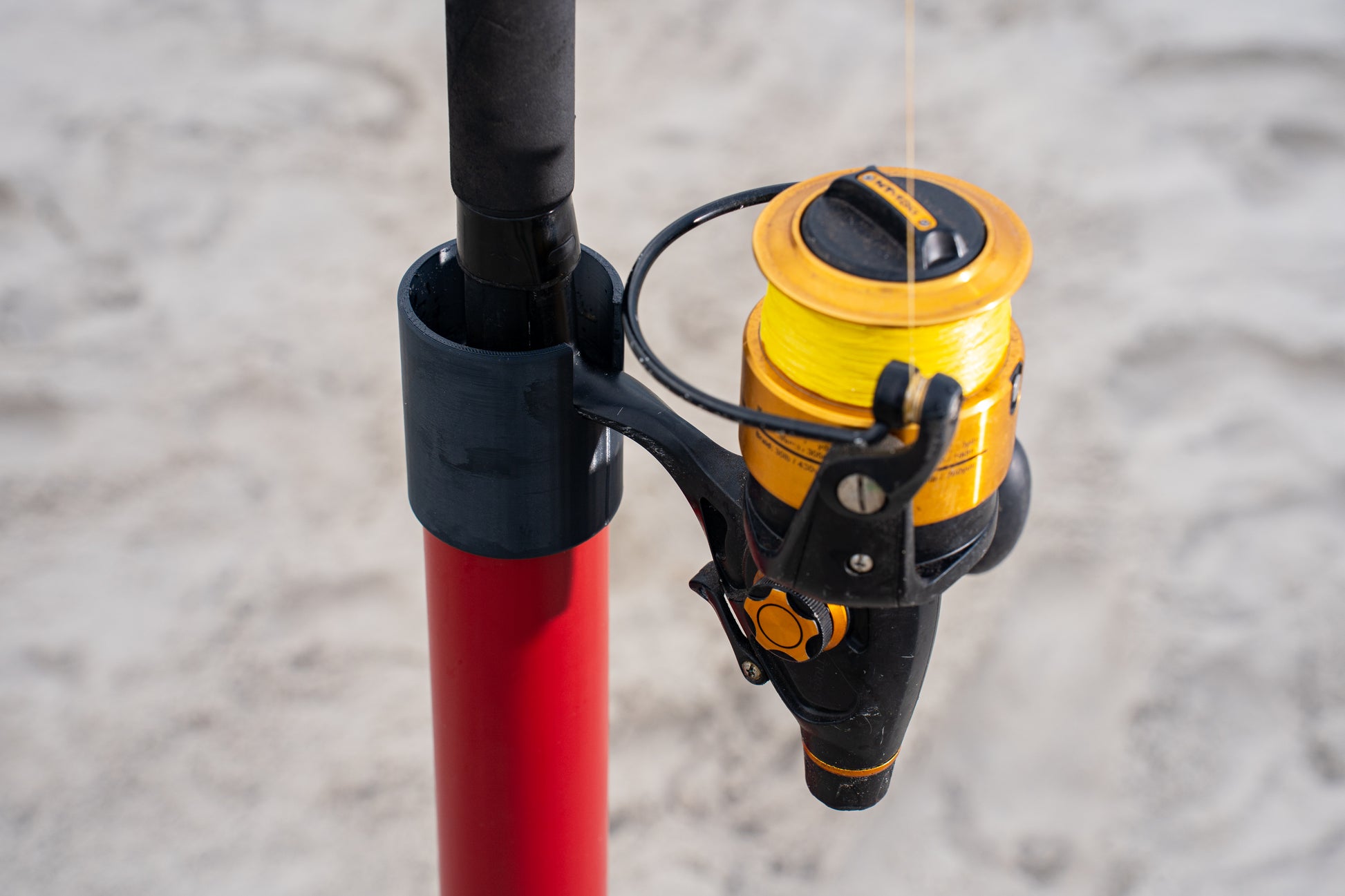 Custom red aluminum surf fishing rod holder beach spike close up with rod inside