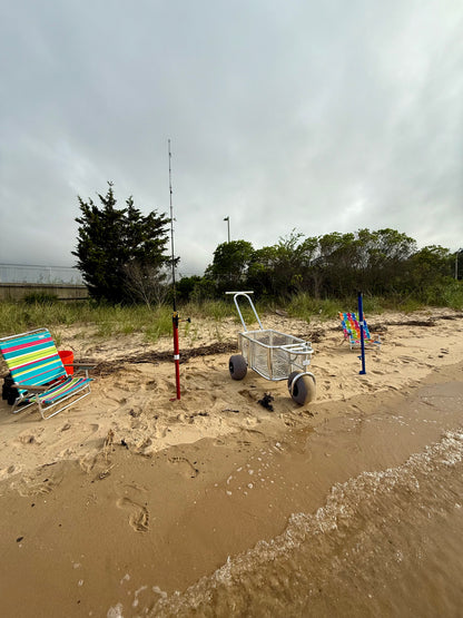 Angler surf fishing buggy, custom aluminum surf fishing cart with rod holders for fishing poles and space for beach gear. set up  at the water's edge with red and blue surf fishing rod holder spikes in the sand.