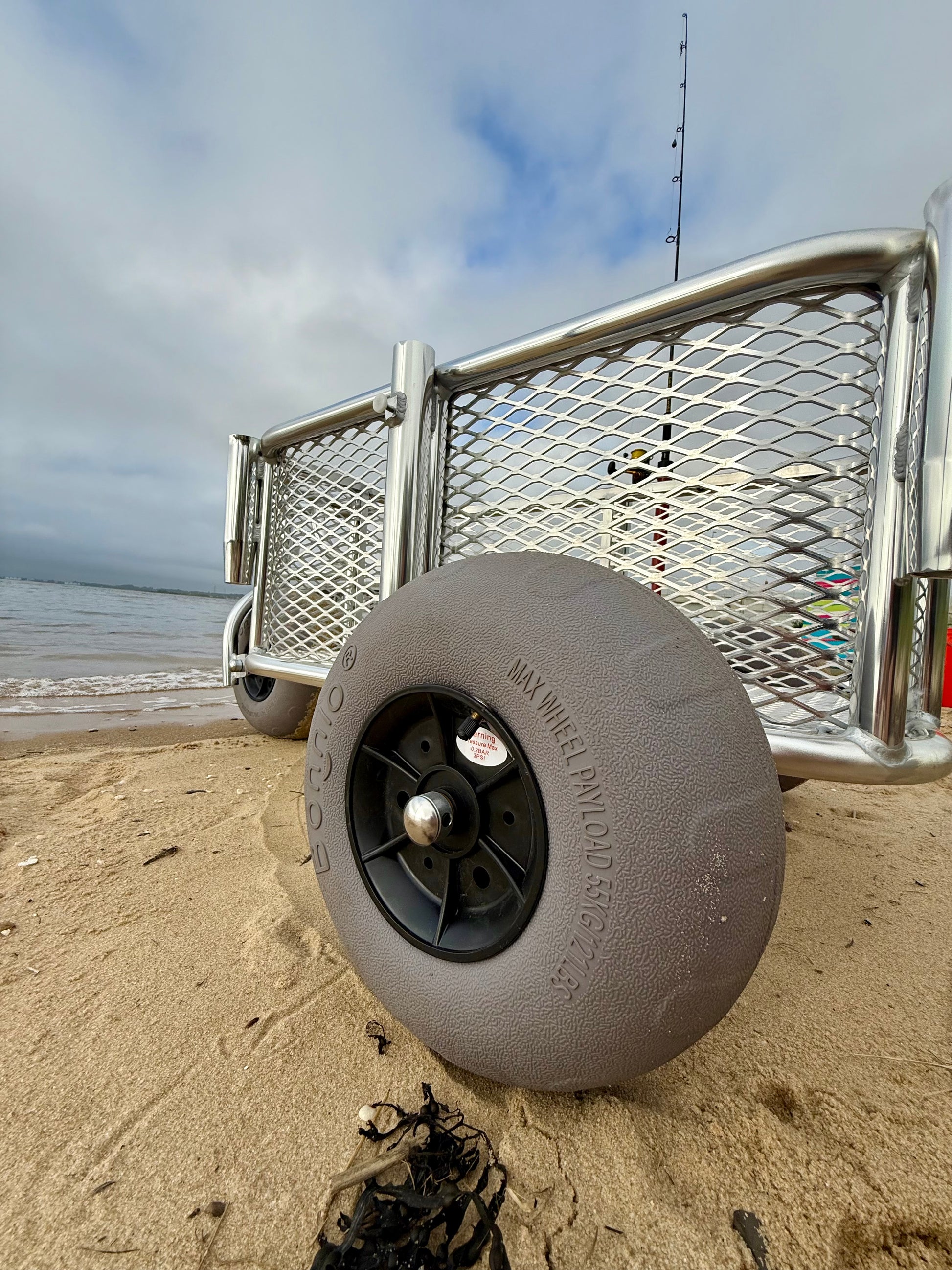 Angler surf fishing buggy, custom aluminum surf fishing cart with rod holders for fishing poles and space for beach gear. close up of balloon tire
